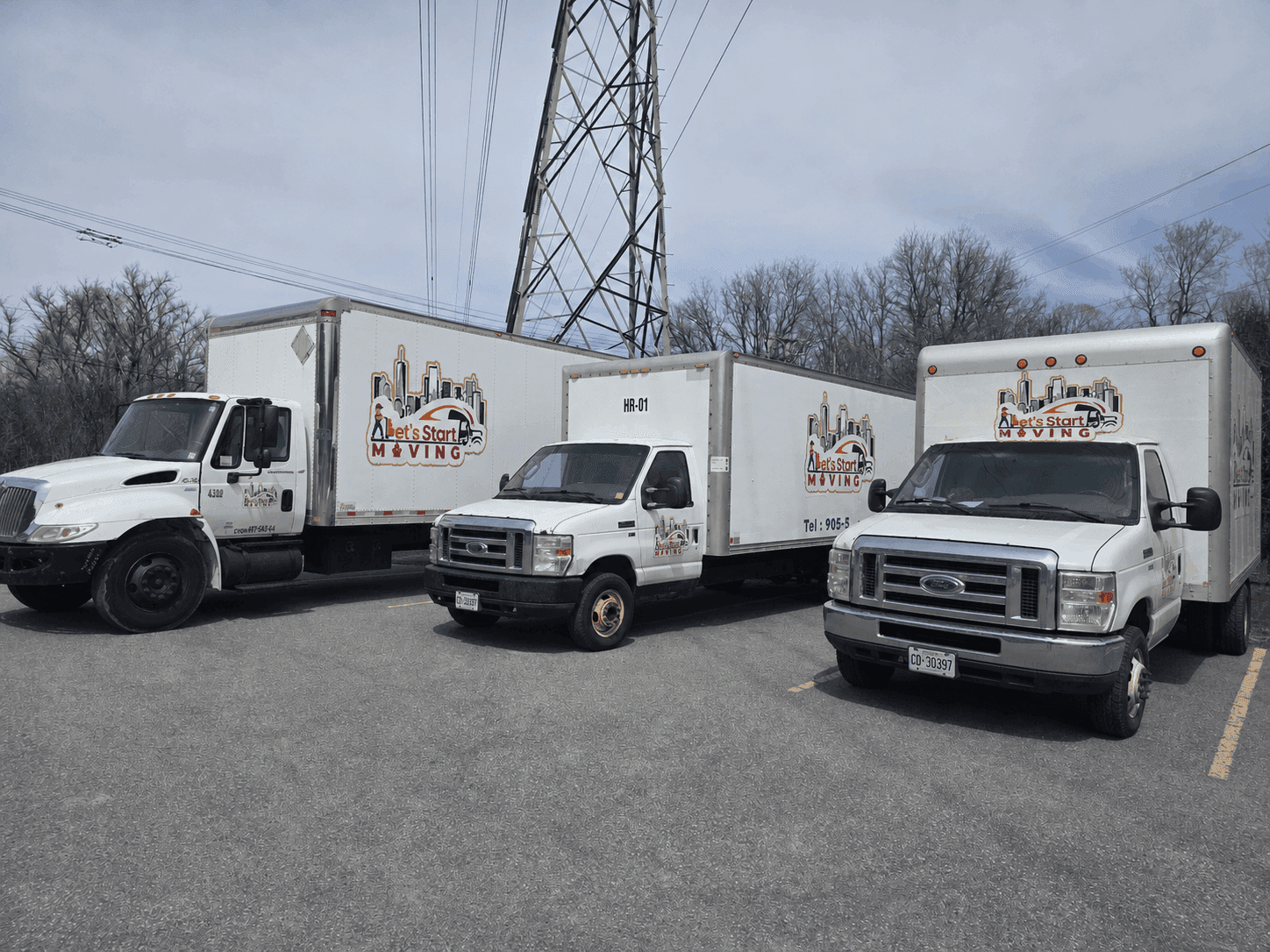 Three Let's Start Moving box trucks of different sizes lined up in a parking lot.